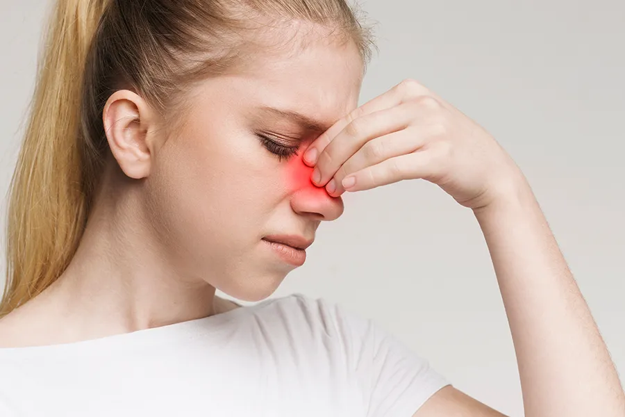 Allergic-Rhinitis-Clinic A woman grimaces and rubs the bridge of her nose due to sinus irritation. Get treatment for allergic rhinitis from Dr. Stephanie King in Salt Lake City.