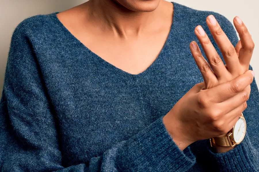 Arthritis-Doctor Close up of a woman in a blue sweater massaging one aching hand with the other. Get help for arthritis from Dr. Stephanie King in Salt Lake City.