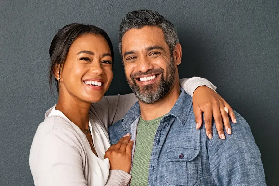 Bioidentical-Hormone-Therapy-Doctor A middle-aged couple with their arms around each other standing against a gray background and smiling, happy with the bioidentical hormone therapy they received from Dr. Stephanie King in Salt Lake City.