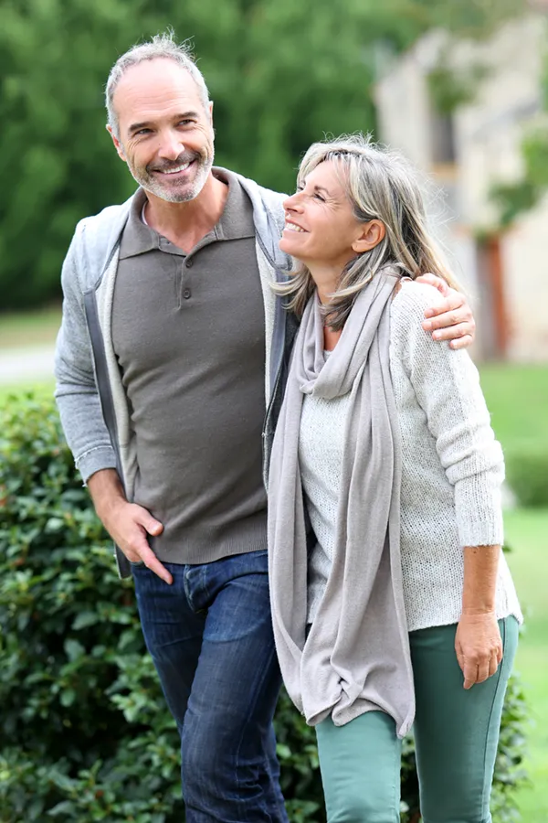 Bioidentical-Hormone-Therapy-Treatment A mature couple in gray toned clothes and jeans walk happily outside, happy with their successful bioidentical hormone treatments from Dr. Stephanie King in Salt Lake City.
