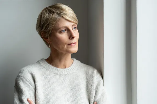 Chronic-Fatigue-Therapy A blond, middle-aged woman looks out the window with a tired expression. Get chronic fatigue treatment from Dr. Stephanie King in Salt Lake City.
