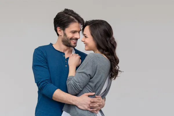 Erectile-Dysfunction-Doctor A man in a blue shirt embracing a woman in a gray shirt smiles due to his successful erectile dysfunction care from Dr. Stephanie King in Salt Lake City.