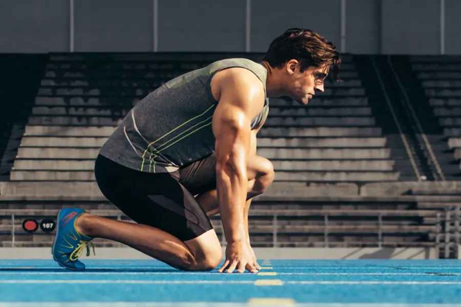 Lean-Muscle-and-Recovery-Clinic A white man kneels at the starting line on a track, determined to do his best. Get treatment for lean muscle loss and recovery from Dr. Stephanie King in Salt Lake City.