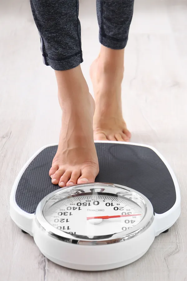 Obesity-Treatment Close up of feet stepping onto a scale. Receive expert functional medicine for obesity treatment by Dr. Stephanie King in Salt Lake City.