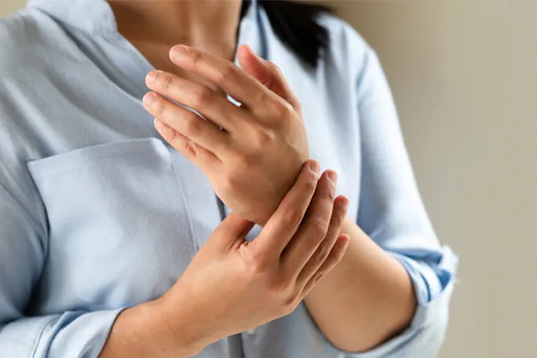 Rheumatoid-Arthritis-Clinic Close up of a woman in a blue blouse rubbing her wrist. Get rheumatoid arthritis treatment from Dr. Stephanie King in Salt Lake City.