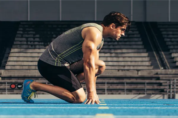 Sermorelin-Clinic With a determined look, Aamuscular man in track clothes kneels at the start of a race. Get Sermorelin peptide therapy from Dr. Stephanie King in Salt Lake City.