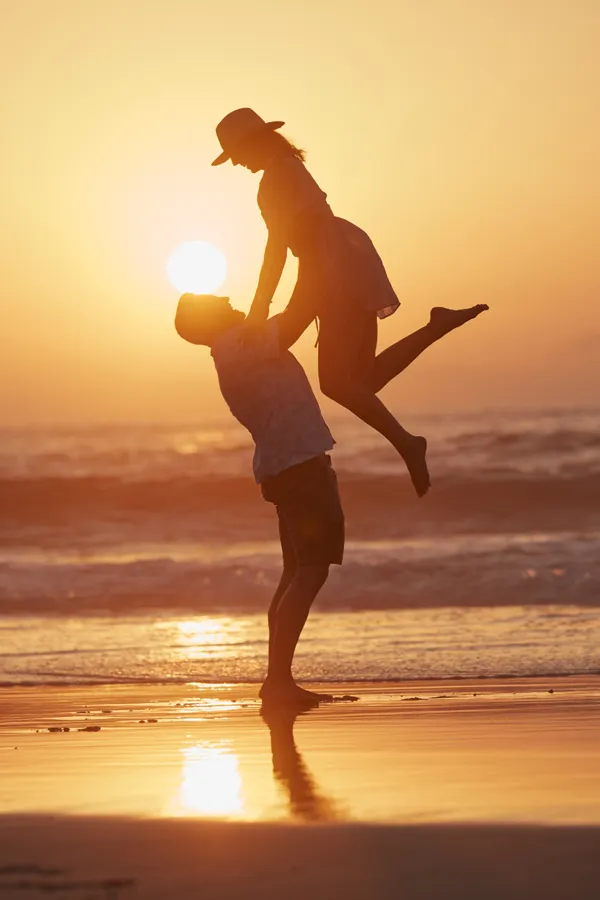 Supplements-Treatment A husband lifts his wife on a beach at sunset. Get nutritional supplement consultation from Dr. Stephanie King in Salt Lake City.