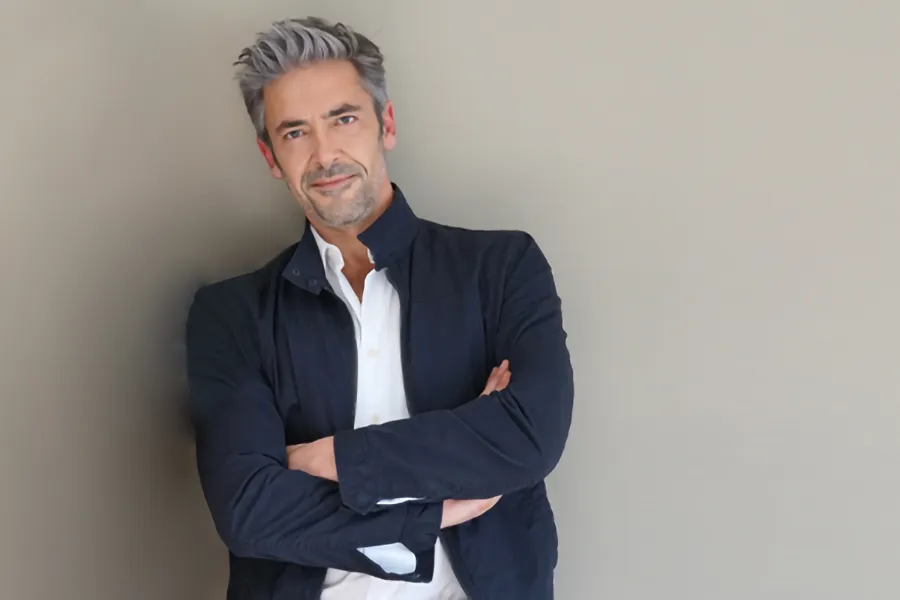 Testosterone-Low-T-Solutionsn-Clinic A middle-aged man in a white shirt and dark blue jacket leans against a gray wall smiling. Get testosterone for Low T from Dr. Stephanie King in Salt Lake City.